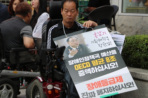 1일 사회보장위원회 앞에서 열린 전국장애인차별철폐연대 '장애등급제 진짜 폐지 예산 쟁취' 집중집회 참가자가 피켓을 목에 걸고 있다. ⓒ에이블뉴스