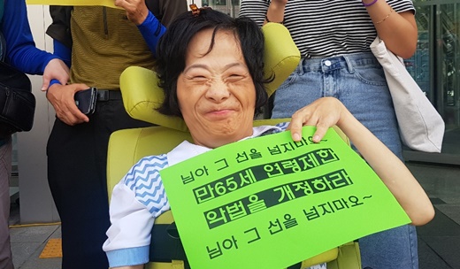 '만 65세 연령제한 악법을 개정하라'는 피켓을 들고있는 중증장애인 활동가.ⓒ에이블뉴스
