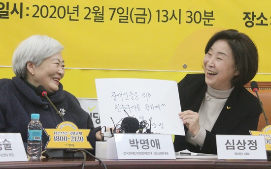 7일 정책협약식에 참석한 전국장애인차별철폐연대 박명애 상임공동대표가 심상정 대표에게 심 대표가 2017년 직접 작성한 ‘장애인들을 위한 민주주의를 향하여^^’ 문구를 보여주며 웃고 있다.ⓒ에이블뉴스