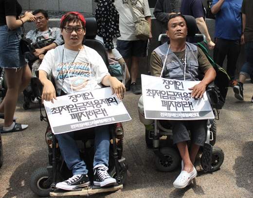 '장애인 최저임금 적용제외 폐지하라' 피켓을 목에 걸고 있는 장애인들.ⓒ에이블뉴스DB