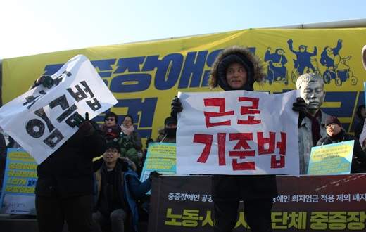 전국장애인차별철폐연대가 지난 2017년 12월 12일 서울 동대문 평화시장 앞에 위치한 전태일 다리에서 최저임금법, 근로기준법 화형식을 하고 있다.ⓒ에이블뉴스DB