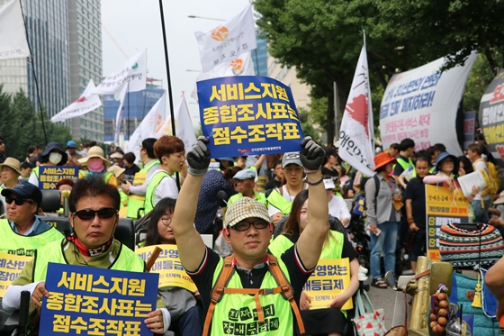 21일 서울 충정로 사회보장위원회 앞에서 열린 '장애등급제 예산 쟁취 및 활동지원 연령제한 폐지 집중결의대회'에서 한 참가자가 '서비스지원 종합조사표는 점수조작표'라 적힌 피켓을 들고 있다. ⓒ에이블뉴스