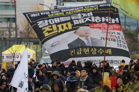 3일 서울 여의도 국회의사당역 인근에서 전국장애인차별철폐연대 주최로 열린 '2019년 세계장애인의 날 투쟁결의대회 및 장애인차별철폐 2020 총선연대 출범식'에 참가한 활동가들 뒤로 기획재정부의 소극적인 예산 집행을 비판하는 내용이 적힌 대형 현수막이 나부끼고 있다. ⓒ에이블뉴스 