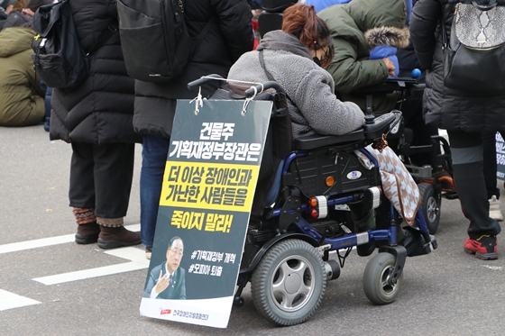 3일 서울 여의도 국회의사당역 인근에서 전국장애인차별철폐연대 주최로 열린 '2019년 세계장애인의 날 투쟁결의대회 및 장애인차별철폐 2020 총선연대 출범식'에 참가한 한 활동가가 피켓을 걸어놓은 휠체어를 타고 있다. ⓒ에이블뉴스 