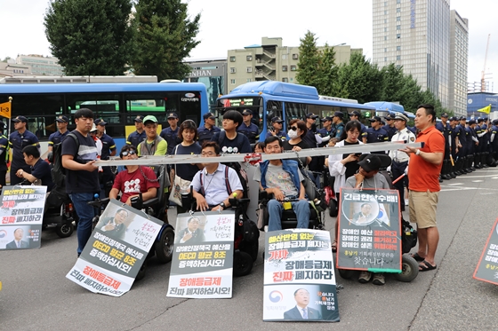 1일 사회보장위원회 앞에서 열린 전국장애인차별철폐연대 '장애등급제 진짜 폐지 예산 쟁취' 집중집회 참가자들이 도로 위에서 사다리를 목에 걸고 예산 증액을 요구하고 있다. ⓒ에이블뉴스