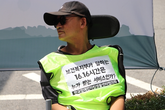 '보건복지부가 말하는 16.16시간은 누가 받는 서비스인가?'라는 문구가 쓰인 조끼를 입은 한국장애인자립생활센터협의회 최강민 조직실장.ⓒ에이블뉴스