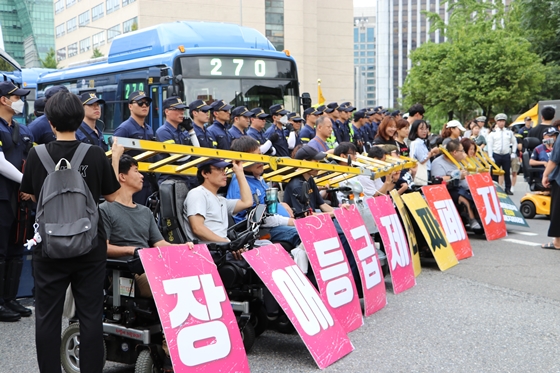 1일 사회보장위원회 앞에서 열린 전국장애인차별철폐연대 '장애등급제 진짜 폐지 예산 쟁취' 집중집회 참가자들이 도로 위에서 사다리를 목에 걸고 예산 증액을 요구하고 있다. ⓒ에이블뉴스