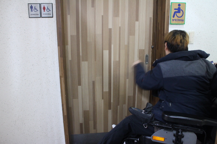 민원복지동 1층 민원실 남녀비장애인화장실 앞에 마련된 남녀공용장애인화장실. 출입문이 출입문은 손이 불편하거나 휠체어를 사용하기 힘든 미닫이로 오목손잡이까지 설치돼 있어 휠체어를 사용하는 장애인이 이용하는데 불편을 겪는다. ⓒ박종태