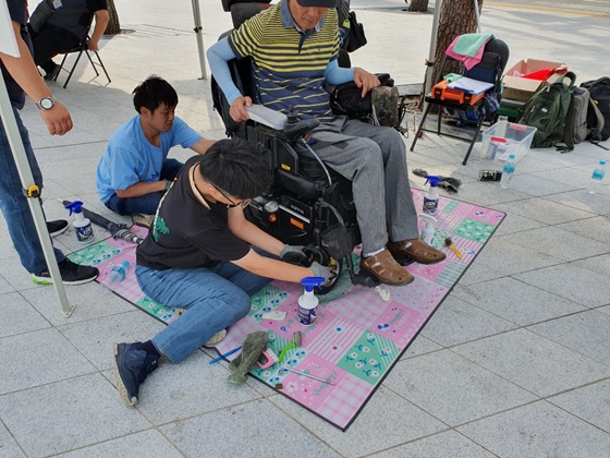 지난 27일 서울 중구 동대문디자인플라자 앞에서 중구길벗장애인자립생활센터가 주최한 '2019년 중구지역 장애인 인식개선 캠페인'에서 장애인 보장구 세척사들이 장애인들의 휠체어를 세척하고 있다. ⓒ에이블뉴스